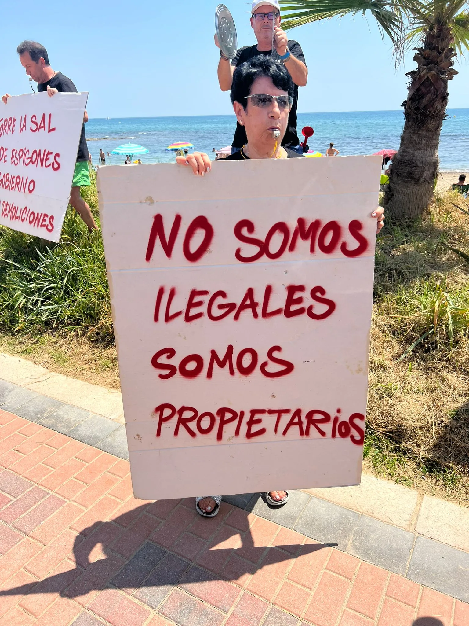 Vecina de Torre la Sal con un cartel de protesta junto a la playa